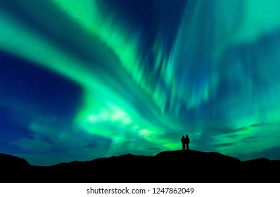 Aurora borealis with silhouette love romantic couple on the mountain.Honeymoon travel concept - Shutterstock ID 1247862049