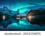 Aurora borealis, snowy mountains, sea, fjord, reflection in water, street lights at starry winter night. Lofoten, Norway. Northern lights. Landscape with polar lights, snowy rocks, sky with stars