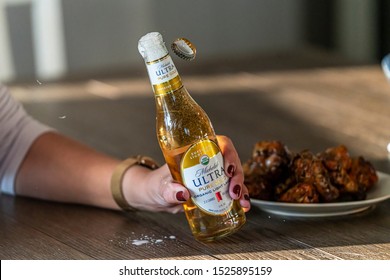 Aurora, CO / USA 10/01/2019: Michelob Ultra Bottle Being Opened Next To A Plate Of Wings