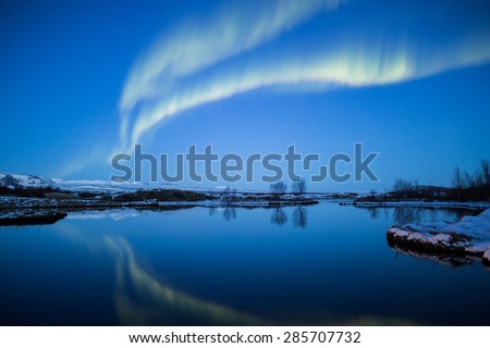 Aurora northern lights mirror reflection in mountain lake at sunset, Thingvellir, Iceland