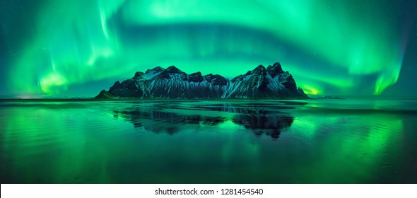 Aurora reflections on Stokksnes black beach with Vestrahorn mountains in center, Iceland
