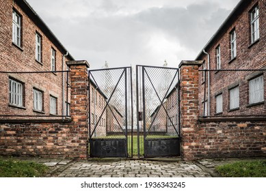 Auschwitz Concentration And Extermination Camp Museum Poland 17.9.19 Red Brick WW2 Nazi Germany Barracks Big Rusty Metal Gates With Steel Mesh Open Onto Cobbled Street To Detain Jewish Prisoners
