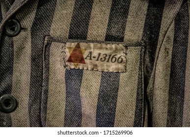 Auschwitz, Poland - November 29 2019: Striped prison uniforms and sewn serial number of Holocaust victims tortured during Nazi terror in Auschwitz concentration camp in Poland during World War II