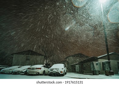 Austin, Texas - Feb 15, 2021: Night View Of The Blizzard In Austin, Texas. The Snow Is Blowing Strongly. The Road, The Cars And The Buildings Are Covered By Snow.