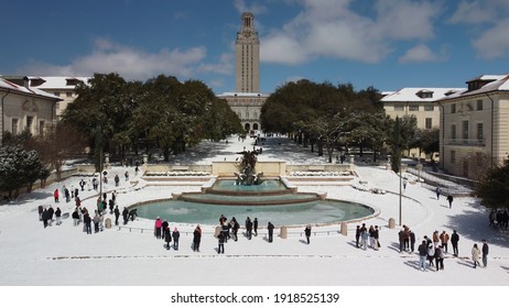 Austin, Texas - February 15, 2021: College students play in the snow near the University of Texas fountain and tower after a snow storm