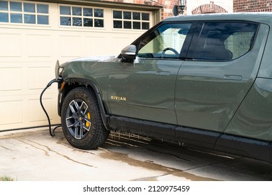 Austin , Texas , USA - February 2nd 2021: Frozen Winter Storm freezes the Rivian R1T Electric Pick Up Truck with Ice cycles and snow covered EV while on Home Charger 
