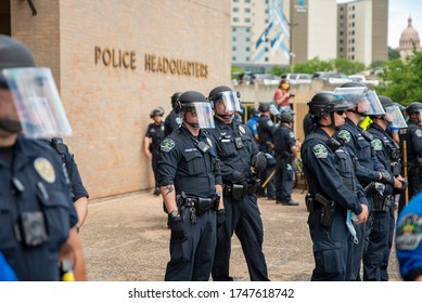 Austin, Texas / USA - May 30, 2020: Police officers watch protesters demonstrating against police brutality outside of City of Austin Police Department headquarters in downtown.