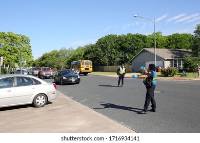 Austin, TX / USA - Apr. 15, 2020: A Female Police Officer Directs A Line Of Cars Into The Parking Lot Of A High School To Receive Emergency Food Aid From The Central Texas Food Bank.