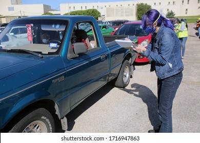 Austin, TX / USA - Apr. 15, 2020: A Female Volunteer Registers A Man In A Line Of Cars In The Parking Lot Of A High School To Receive Emergency Food Aid From The Central Texas Food Bank.