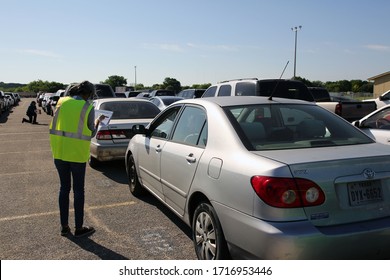 Austin, TX / USA - Apr. 15, 2020: A Female Volunteer Registers A Woman In A Line Of Cars In The Parking Lot Of A High School To Receive Emergency Food Aid From The Central Texas Food Bank.