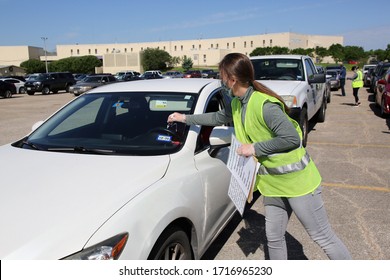 Austin, TX / USA - Apr. 15, 2020: A Female Volunteer Marks A Car In A Line Of Vehicles In The Parking Lot Of A High School To Receive Emergency Food Aid From The Central Texas Food Bank.