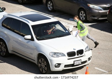 Austin, TX / USA - Apr. 15, 2020: A Female Volunteer Registers A Man In A Line Of Cars In The Parking Lot Of A High School To Receive Emergency Food Aid From The Central Texas Food Bank.