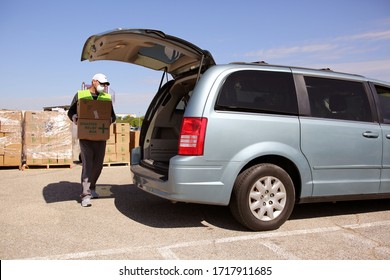 Austin, TX / USA - Apr. 15, 2020: A Volunteer Distributes Emergency Food Aid From The Central Texas Food Bank To People In Need At A High School Parking Lot While Maintaining Social Distancing.