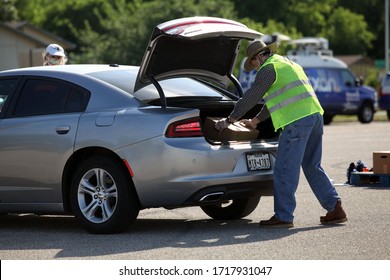 Austin, TX / USA - Apr. 15, 2020: A Male Volunteer Distributes Emergency Food Aid From The Central Texas Food Bank To People In Need At A High School Parking Lot While Maintaining Social Distancing.