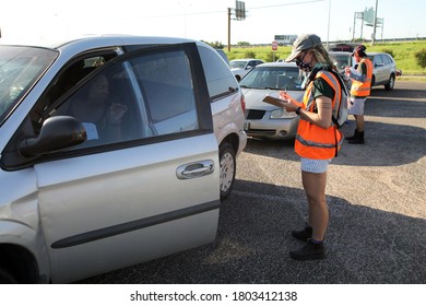 Austin, TX / USA - Apr. 15, 2020: A Female Volunteer Registers A Woman In A Line Of Cars In The Parking Lot Of A High School To Receive Emergency Food Aid From The Central Texas Food Bank.