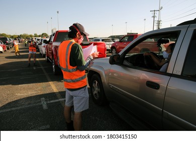 Austin, TX / USA - Apr. 15, 2020: A Male Volunteer Registers A Woman In A Line Of Cars In The Parking Lot Of A High School To Receive Emergency Food Aid From The Central Texas Food Bank.