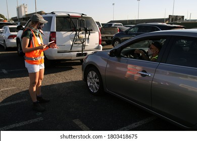 Austin, TX / USA - Apr. 15, 2020: A Female Volunteer Registers A Man In A Line Of Cars In The Parking Lot Of A High School To Receive Emergency Food Aid From The Central Texas Food Bank.