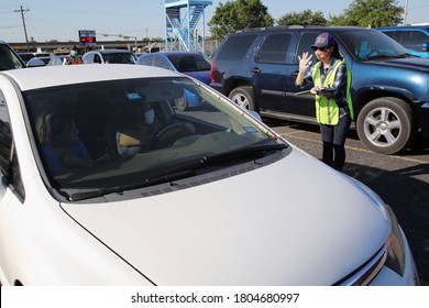 Austin, TX / USA - Apr. 15, 2020: A Female Volunteer Registers A Woman In A Line Of Cars In The Parking Lot Of A High School To Receive Emergency Food Aid From The Central Texas Food Bank.