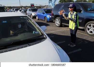 Austin, TX / USA - Apr. 15, 2020: A Female Volunteer Offers Census Info To A Woman In A Line Of Cars In The Parking Lot Of A High School To Receive Emergency Food Aid From The Central Texas Food Bank.