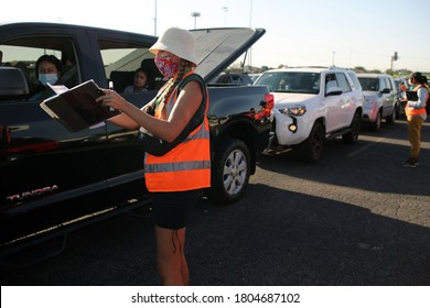 Austin, TX / USA - Apr. 15, 2020: A Female Volunteer Registers A Woman In A Line Of Cars In The Parking Lot Of A High School To Receive Emergency Food Aid From The Central Texas Food Bank.