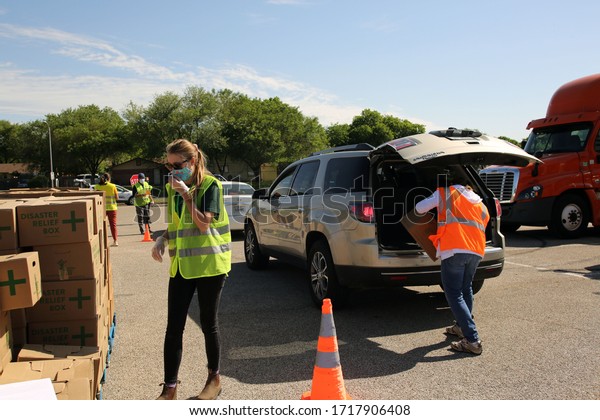 Austin,\
TX / USA - Apr. 15, 2020: Volunteers distribute emergency food aid\
from the Central Texas Food Bank to people in need at a high school\
parking lot while maintaining social\
distancing.