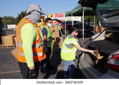 Austin, TX / USA - Aug. 20, 2020: Two Male And A Female Volunteer Distribute Emergency Food Aid From The Central Texas Food Bank To People In Need At A High School Parking Lot.