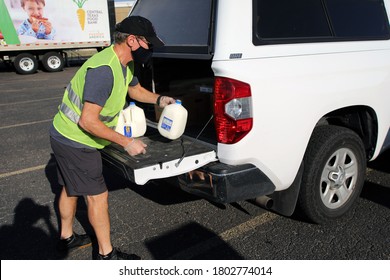 Austin, TX / USA - Aug. 20, 2020: A Male Volunteer Distributes Emergency Milk Aid From The Central Texas Food Bank To People In Need At A High School Parking Lot.