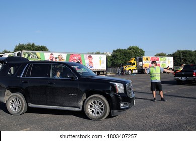 Austin, TX / USA - Aug. 20, 2020: A Male Volunteer Directs Traffic In The Parking Lot Of A High School Where The Central Texas Food Bank Was Distributing Emergency Food Aid.