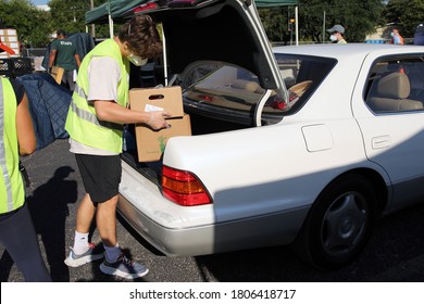 Austin, TX / USA - Aug. 20, 2020: A Male Volunteer Distributes Emergency Food Aid From The Central Texas Food Bank To People In Need At A High School Parking Lot.