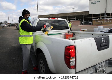 Austin, TX USA - Feb. 21, 2021:  A young male African American volunteer distributes water at a drive through City of Austin event for people in need due to outages caused by a winter storm. 