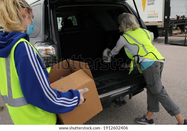 Austin, TX USA - Feb. 4, 2021: Two female\
volunteers distribute emergency food aid from the Central Texas\
Food Bank to people in need at the Expo\
Center.