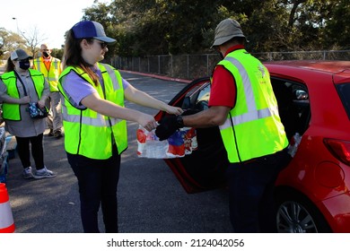 Austin, TX, USA - Feb. 8, 2022:  A Male And Female Volunteer Distribute Free Bottled Water At A High School Football Stadium After A Water Treatment Plant Mishap Caused A City Wide Boil Water Notice. 