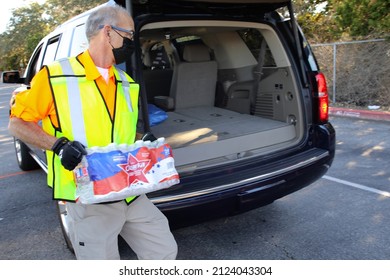 Austin, TX, USA - Feb. 8, 2022:  A Male  Volunteer Distributes Free Bottled Water At A High School Football Stadium After A Water Treatment Plant Mishap Caused A City Wide Boil Water Notice. 