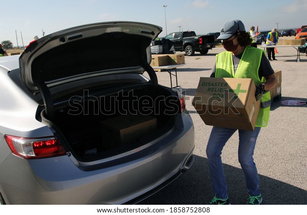 Austin, TX / USA - Nov. 19, 2020: One week before\
Thanksgiving, a female volunteer distributes emergency food aid\
from the Central Texas Food Bank to people in need at the Austin\
Expo Center. 
