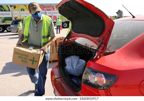 Austin, TX USA - Nov. 19, 2020: One week before\
Thanksgiving, a male volunteer distributes emergency food aid from\
the Central Texas Food Bank to people in need at the Austin Expo\
Center. 