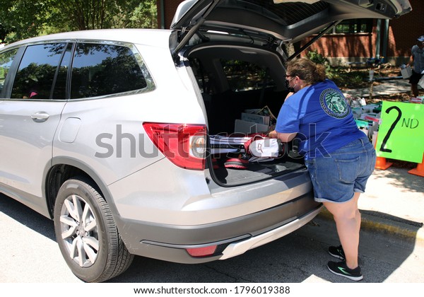 Austin, TX/USA  - Aug. 6, 2020:  An Austin\
Independent School District teacher loads school supplies left at\
an elementary school when schools closed in April due to Covid-19\
into a parent\'s trunk.