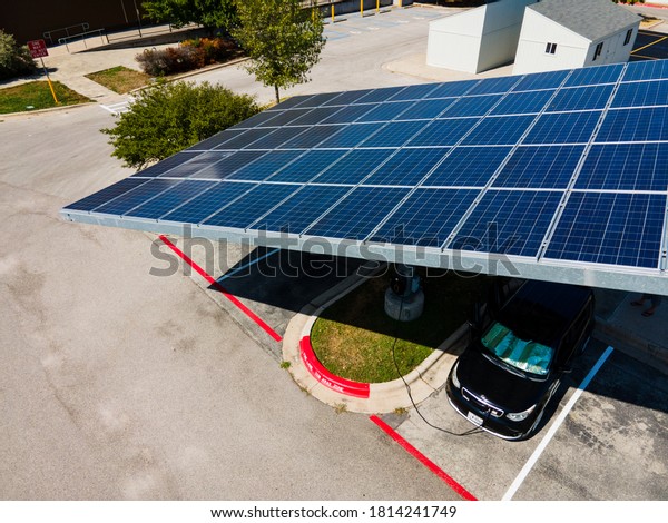 Austin,Texas / USA -\
September 12th 2020: electric vehicle charging under large solar\
panel array creating clean renewable energy fighting climate change\
and lowering energy cost\
