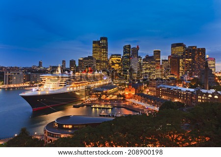 Australia Sydney Circular quay international seaport passenger terminal with docked ocean liner and city CBD in the background illuminated at sunset
