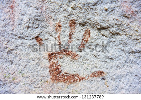 An Australian Aboriginal hand print using red ochre on a white rock wall.