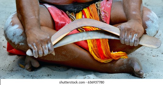 Australian Aboriginal man sitting on the ground holding boomerangs in the tropical far north of Queensland, Australia.