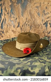 Australian Army Slouch Hat Or Diggers Hat With Badge And A Red Poppy On A Background Of Camouflage Pattern.