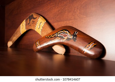 Australian Boomerangs Seen From The Side, Lying On The Vintage Brown Shelf. Souvenirs From Australia On Display In The Living Room.