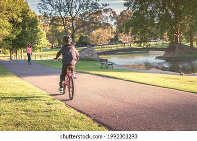 Australian boy riding his bicycle along the bike lane in Adelaide Park Lands on a day
