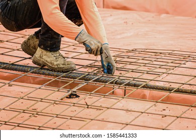 Australian builder performing steel fixing operations with tying tool for a new suburban house slab