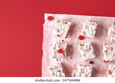 Australian Christmas Dessert With Dried Fruits And Coconut, Cut In Pieces, On Red Background. Flat Lay Of White Cake With Rice. Traditional Xmas Food