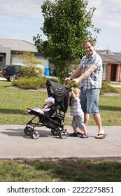 An Australian Father Pushing A Baby In A Pram With His Toddler Son On A Warm Sunny Day