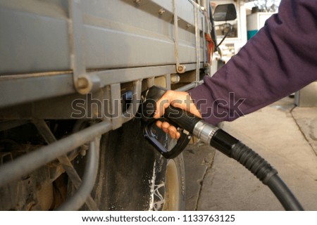 Australian man filling up his 4WD car with fuel from a black petrol bowser, rural New South Wales