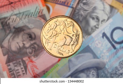 An Australian One Dollar Coin Suspended Over Three Bank Notes.