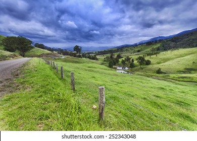 Australian Rural NSW Remote Agricultural Farm With Highly Developed Grazing Land For Steer Production At Cloudy Thunderstorm Weather View From Side Road Over Fence