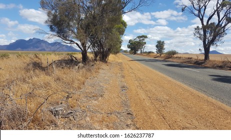Australian rural scenic outback. Long road with hills, blue sky, clouds, trees and farm land.